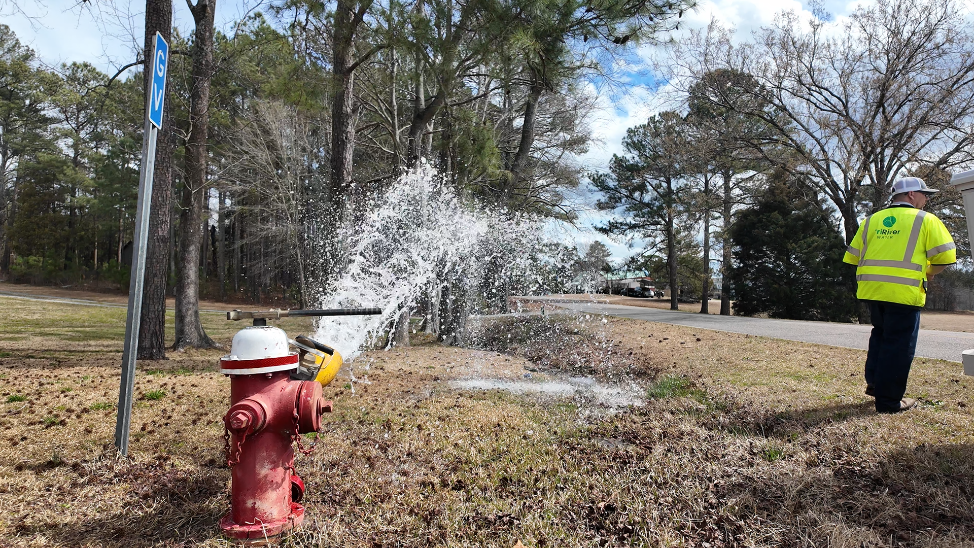 Fire hydrant spewing water with a TriRiver Water employee supervising